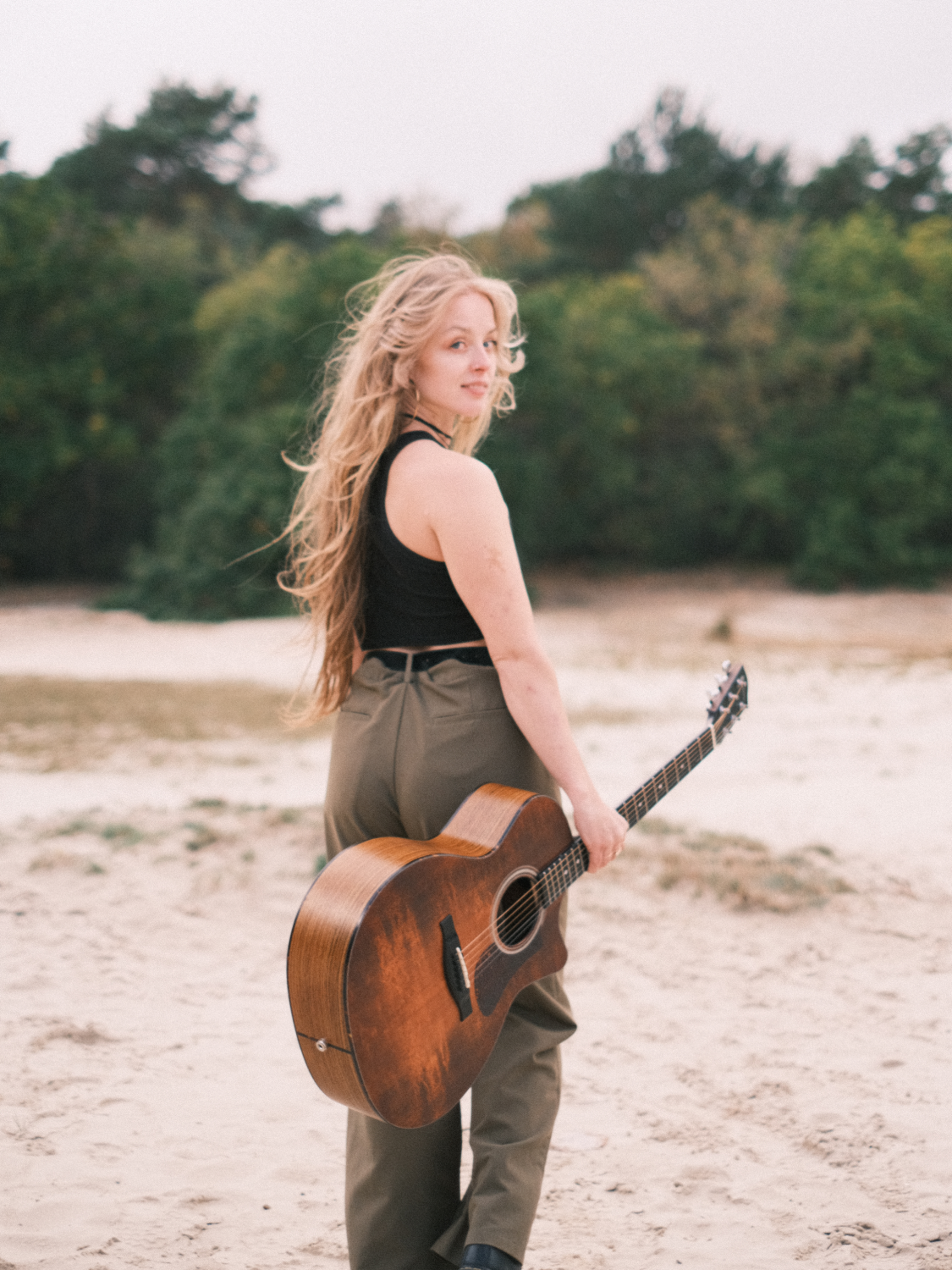 Zangeres Rachelle Adriënne kijkt achterom met gitaar in de hand
